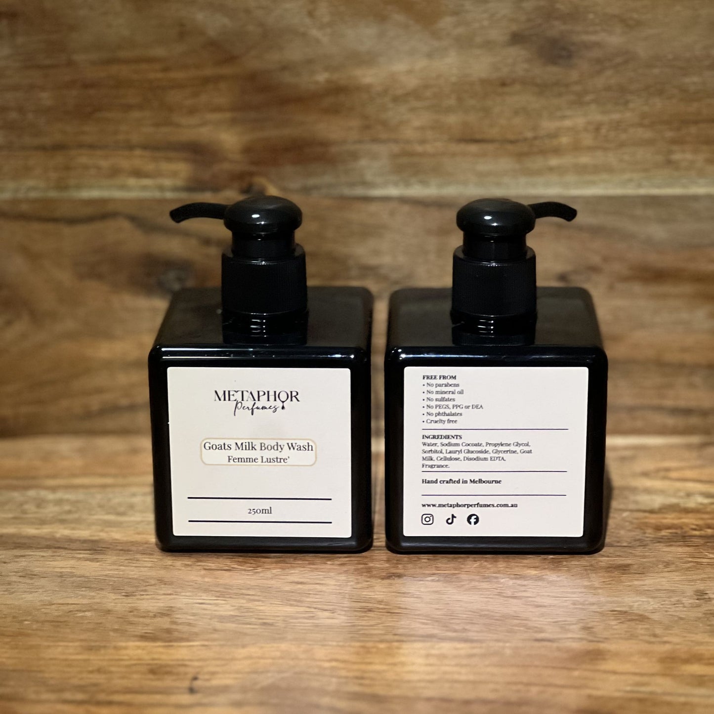 Product image of Metaphor Perfumes goats milk body wash in a black pump bottle on a wooden surface — Femme Lustré, inspired by Dior J’adore.