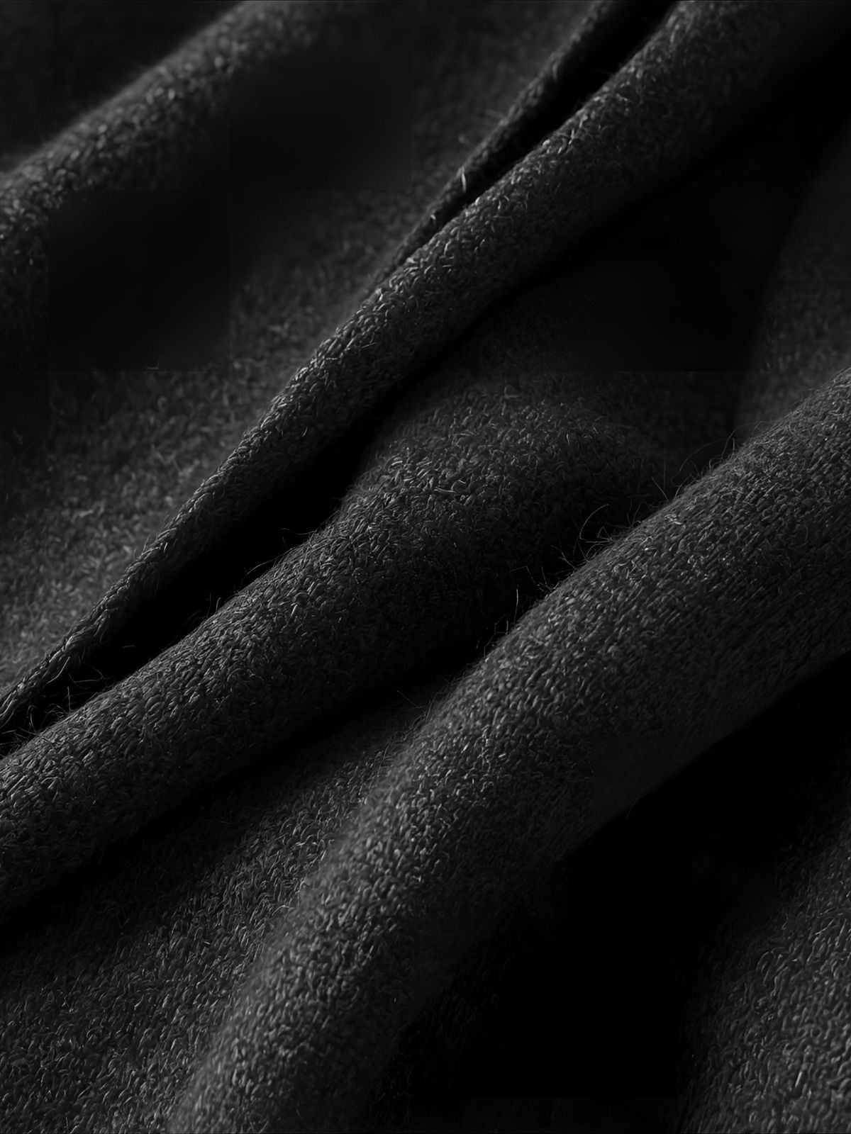 Soft folds of textured wool in deep shadow — evoking quiet strength, grounded elegance, and the masculine restraint of for him extrait de parfum.