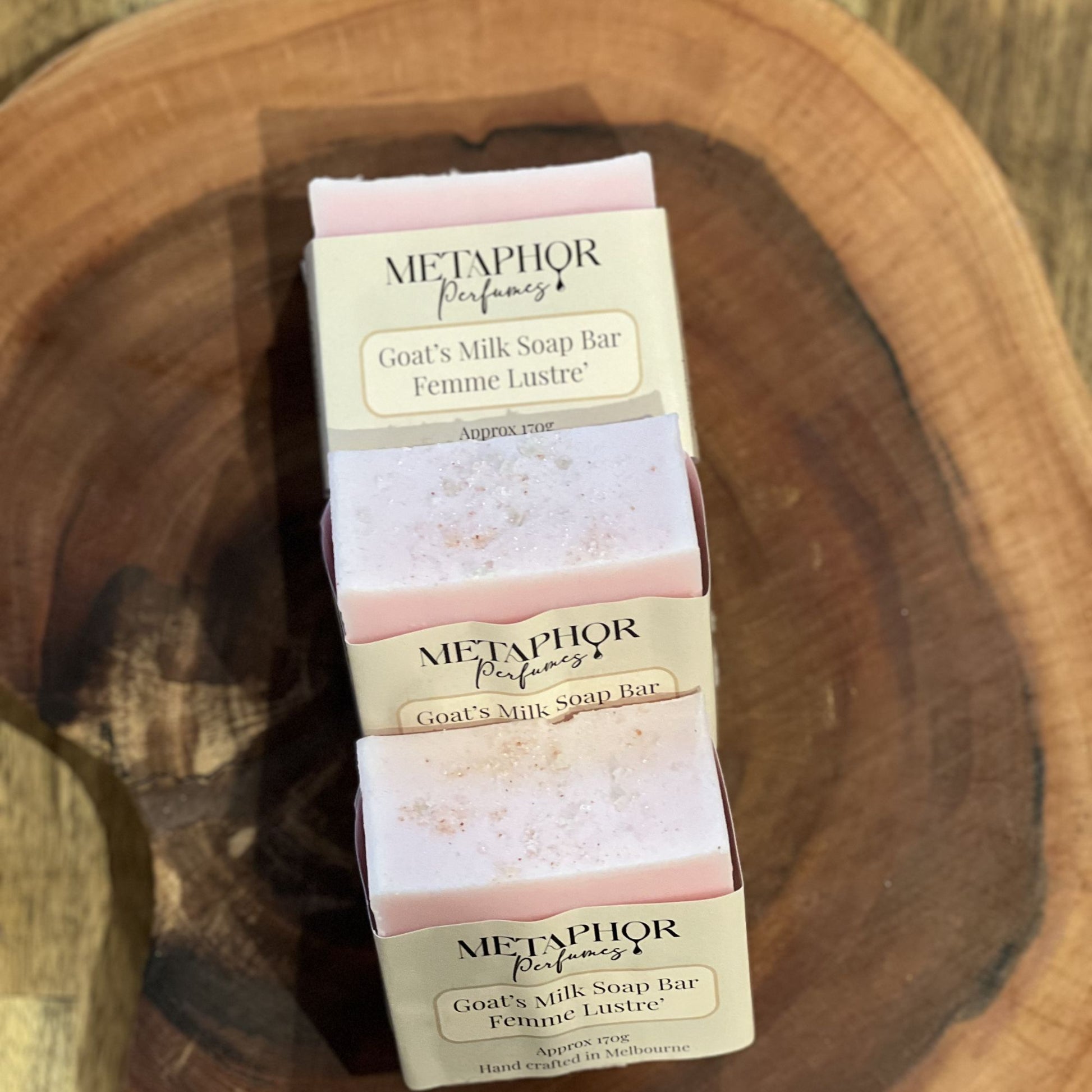 Metaphor Perfumes Femme Lustré goat’s milk soap bars in soft pink tones, wrapped in cream labels on a wooden surface; J’adore‑inspired fragrance