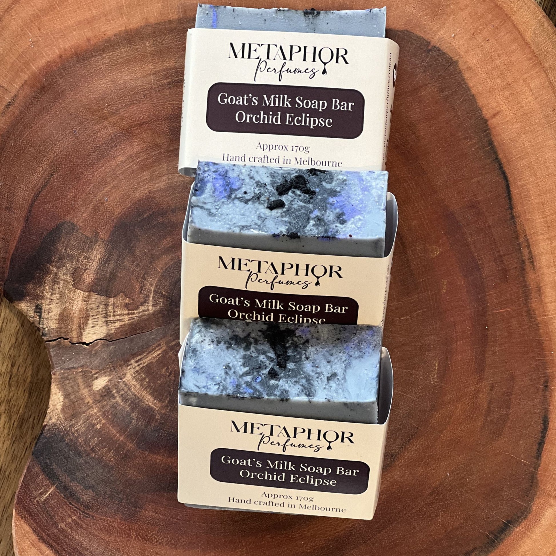 Product image of Metaphor Perfumes goat’s milk soap bar on a wooden surface — Orchid Eclipse, inspired by Tom Ford Black Orchid.