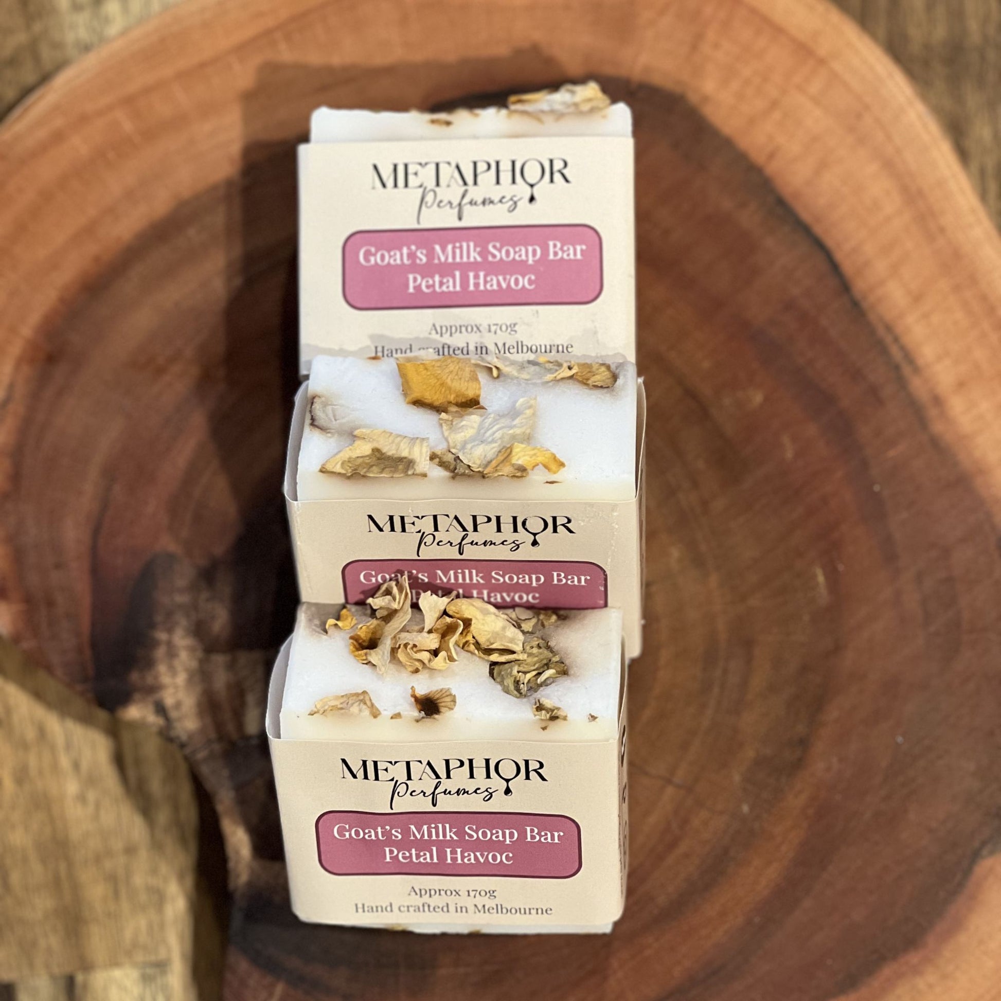 Metaphor Perfumes Petal Havoc goat’s milk soap bars with dried petal tops, displayed on a wooden surface; Flowerbomb‑inspired fragrance