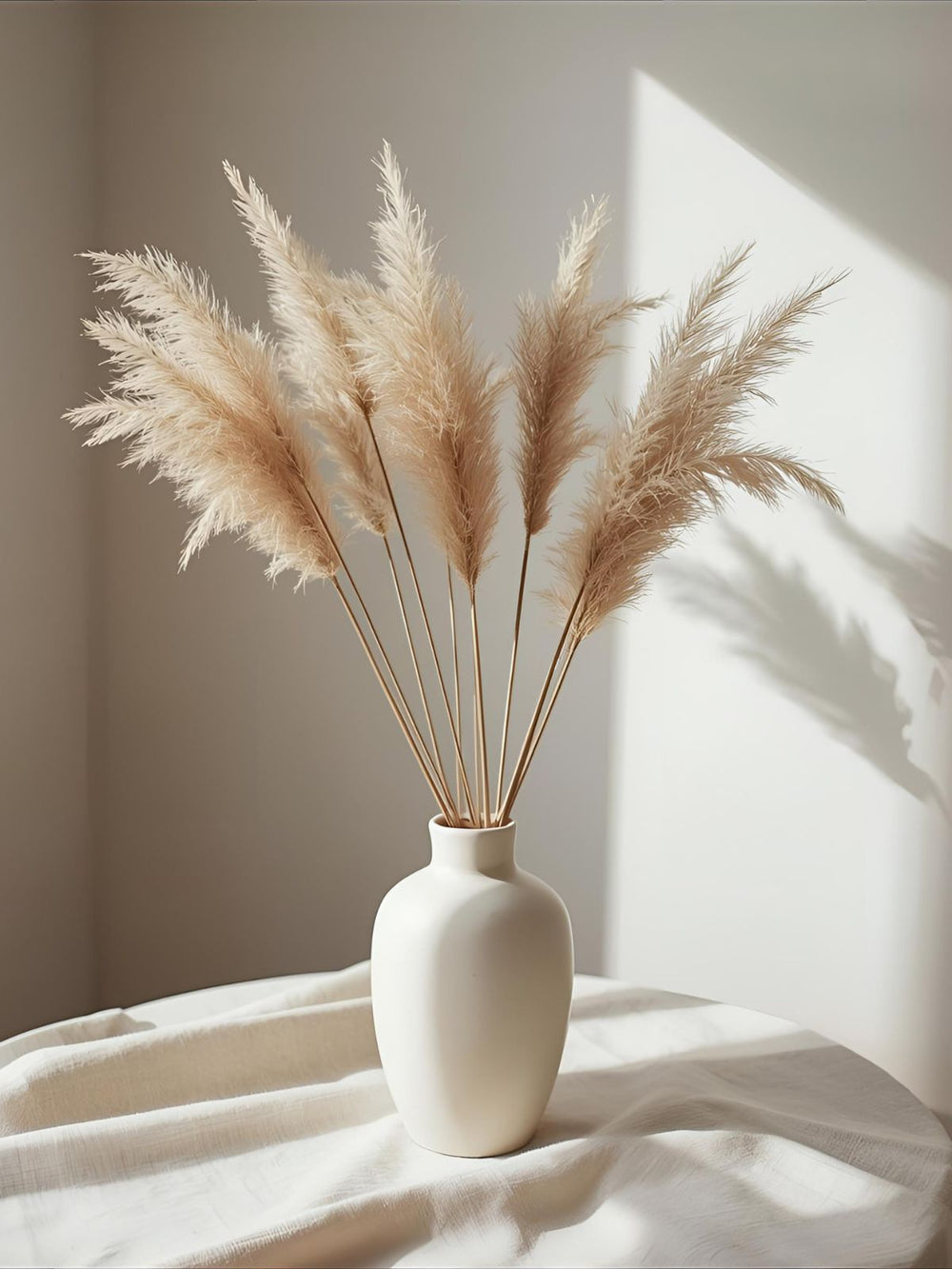 White ceramic vase with dried pampas grass on linen backdrop