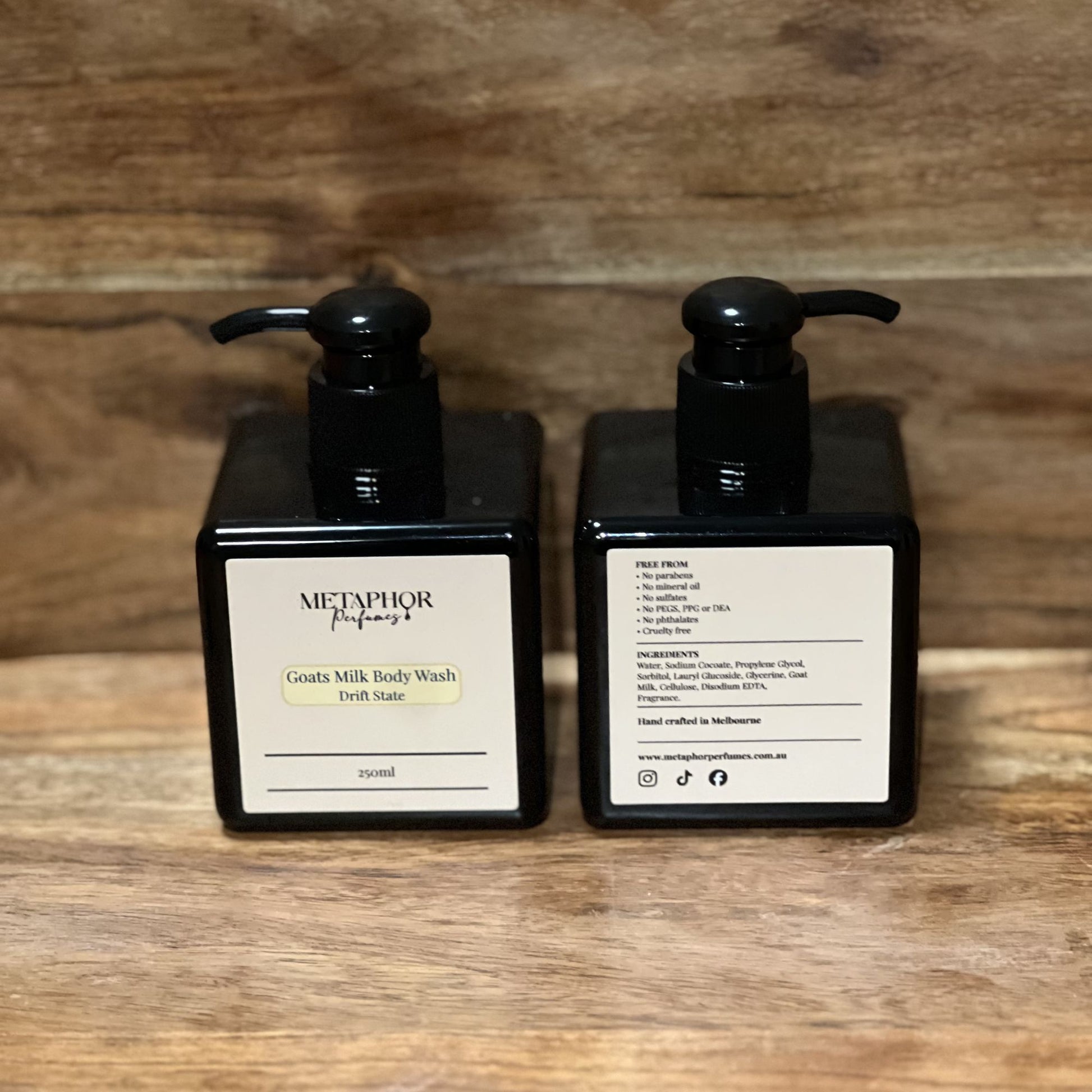 Product image of Metaphor Perfumes goats milk body wash in a black pump bottle on a wooden surface — Drift State, inspired by Louis Vuitton Afternoon Swim.