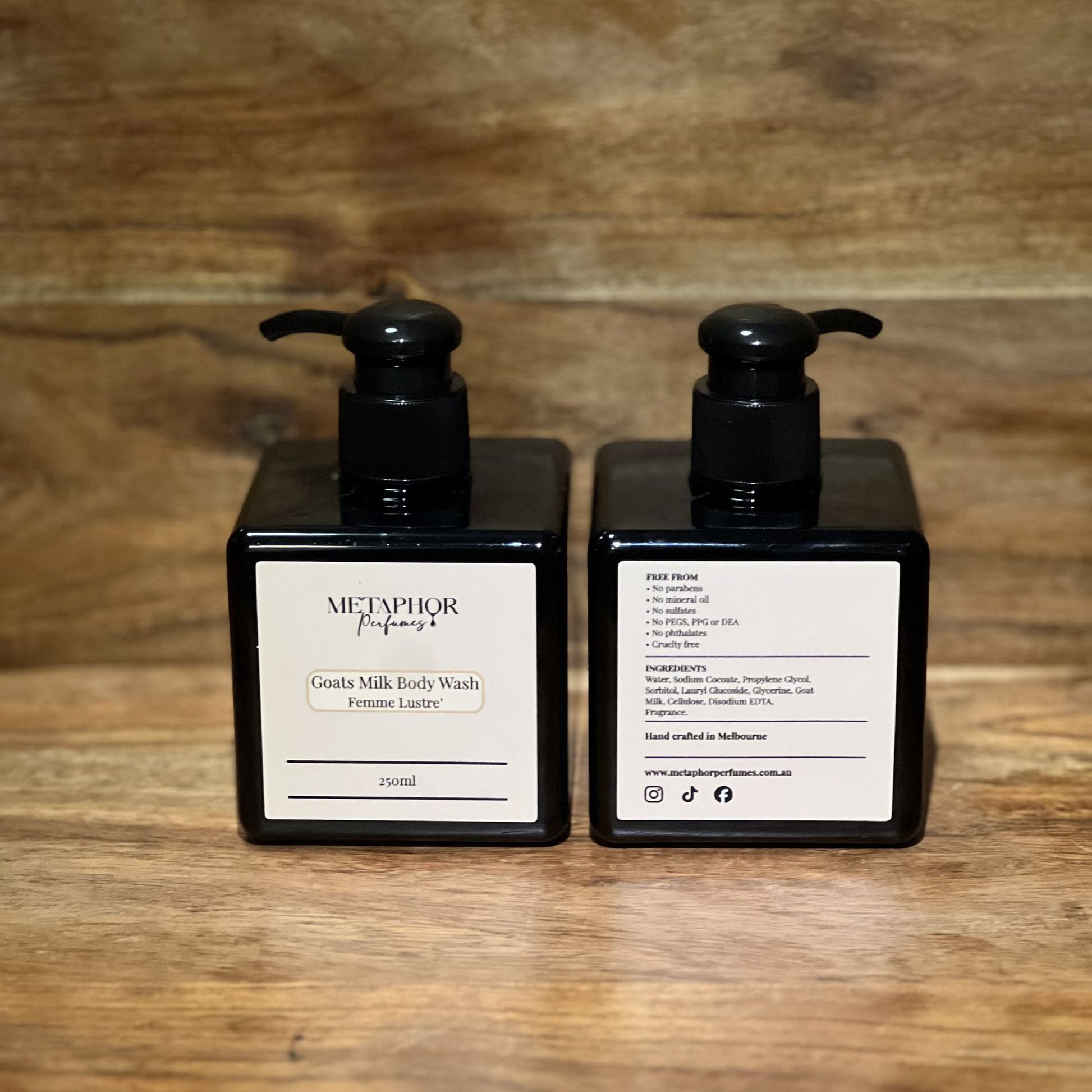 Product image of Metaphor Perfumes goats milk body wash in a black pump bottle on a wooden surface — Femme Lustré, inspired by Dior J’adore.