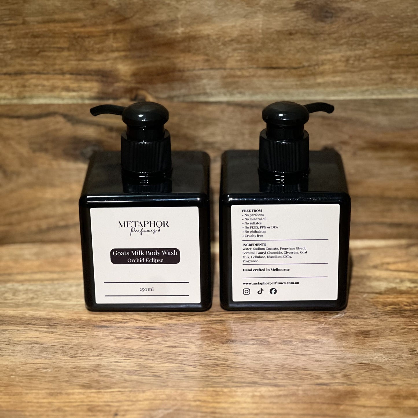Product image of Metaphor Perfumes goats milk body wash in a black pump bottle on a wooden surface — Orchid Eclipse, inspired by Tom Ford Black Orchid.