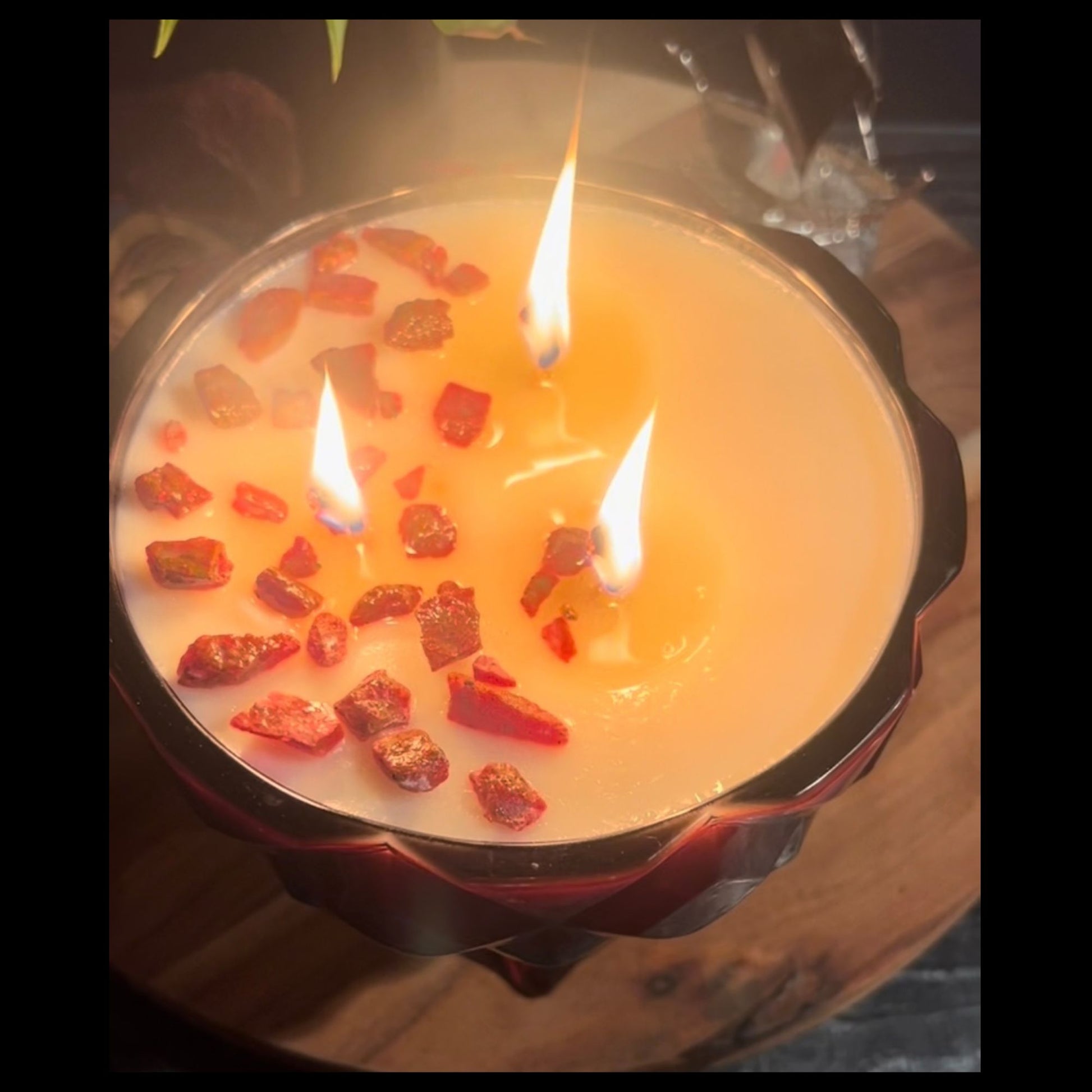 A lit ruby red chalice candle with multiple flames reflecting through the faceted red glass.