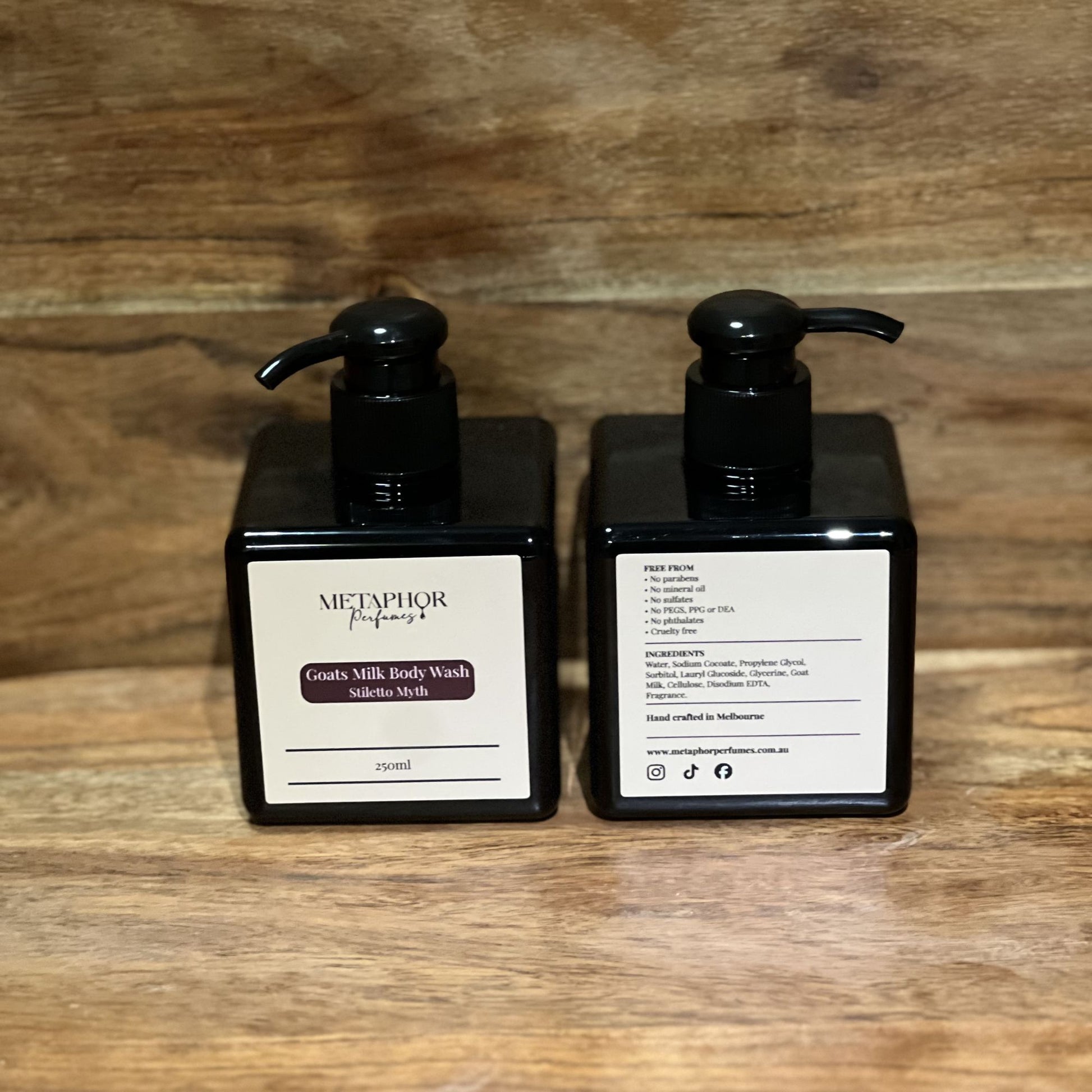 Product image of Metaphor Perfumes goats milk body wash in a black pump bottle on a wooden surface — Stiletto Myth, inspired by Carolina Herrera Good Girl.